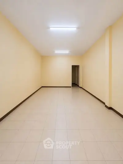 Spacious empty room with tiled flooring and neutral walls, ideal for customization.