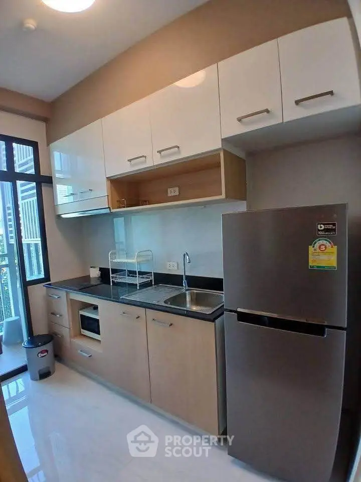 Modern kitchen with sleek cabinets and stainless steel fridge in a high-rise apartment.