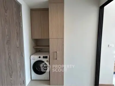 Modern laundry area with built-in washing machine and storage cabinets in a sleek apartment.