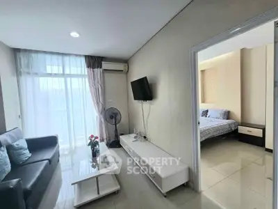 Modern living room with sleek furniture and adjacent cozy bedroom in a bright apartment.