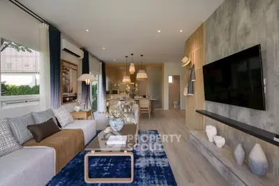 Modern living room with stylish decor and open layout, featuring a large TV and elegant furnishings.
