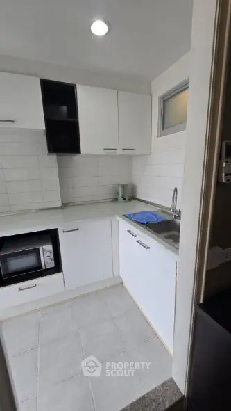 Modern compact kitchen with sleek white cabinets and built-in appliances