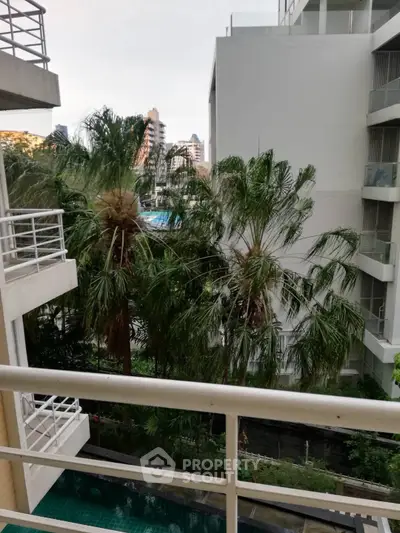 Scenic view from balcony overlooking lush greenery and modern buildings, perfect for urban living enthusiasts.