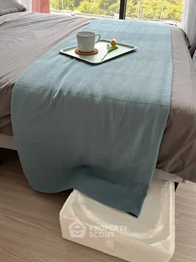 Inviting bedroom with a neatly made bed and a serene color palette, complemented by a cozy breakfast tray, showcasing a tranquil living space.
