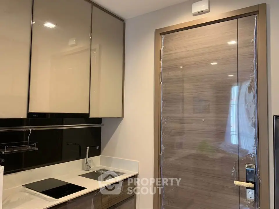 Modern kitchen with sleek cabinets and compact design, featuring a built-in stovetop and sink.