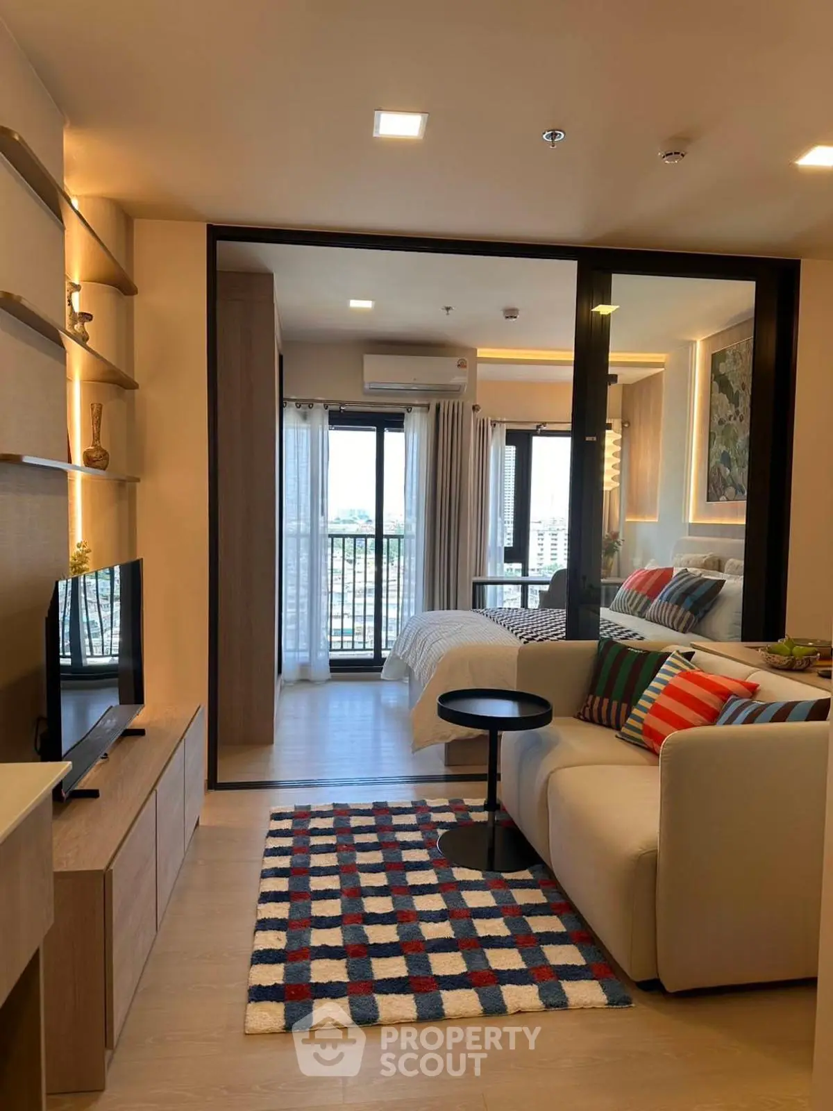 Modern studio apartment with stylish living area and cozy bedroom, featuring floor-to-ceiling windows and vibrant decor.
