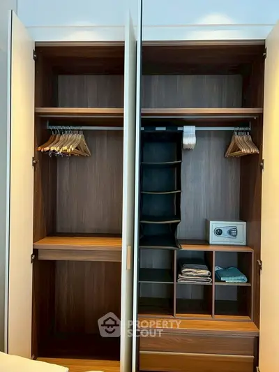 Spacious modern wardrobe with wooden finish and built-in safe, perfect for organized storage in a luxury bedroom.