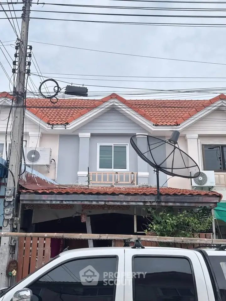 Charming townhouse with red tile roof and satellite dish, perfect for modern living.