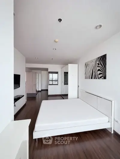 Spacious modern bedroom with minimalist decor and large window view.