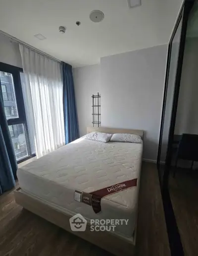 Modern bedroom with large window and minimalist decor in a stylish apartment.