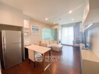 Modern living room with open kitchen, featuring sleek furniture and natural light from large windows.