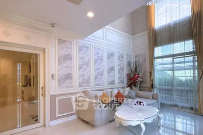 Elegant living room with high ceilings and large windows, featuring a cozy sofa and stylish decor.