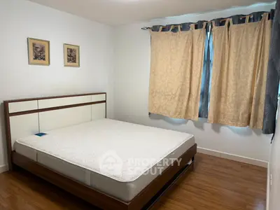 Spacious bedroom with elegant wooden flooring and large window for natural light.
