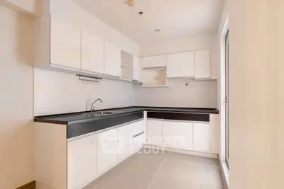 Modern kitchen with sleek white cabinets and black countertops in a spacious layout.