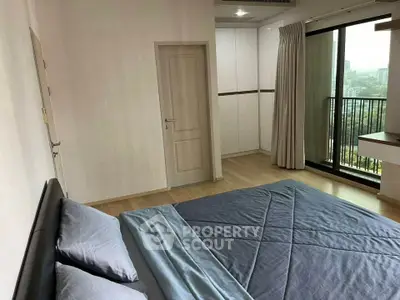 Spacious bedroom with balcony and city view, modern design, ample natural light.