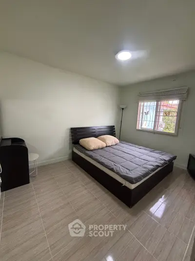 Cozy bedroom with modern bed and natural light from window, perfect for relaxation.