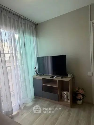 Cozy living room with TV stand and sheer curtains, perfect for relaxation.