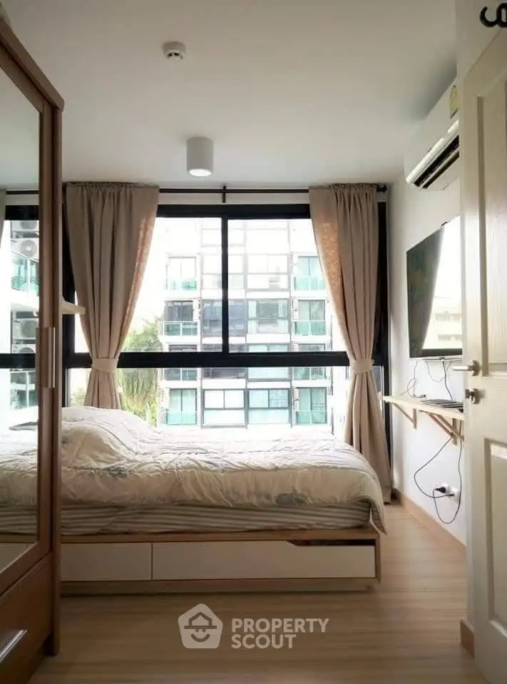 Cozy bedroom with large window and modern furnishings in urban apartment
