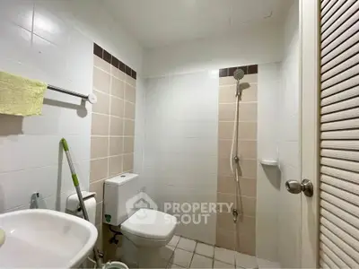 Compact bathroom with shower and toilet in neutral tones