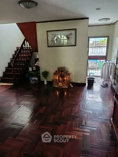 Spacious living room with wooden flooring and staircase, ideal for family gatherings.