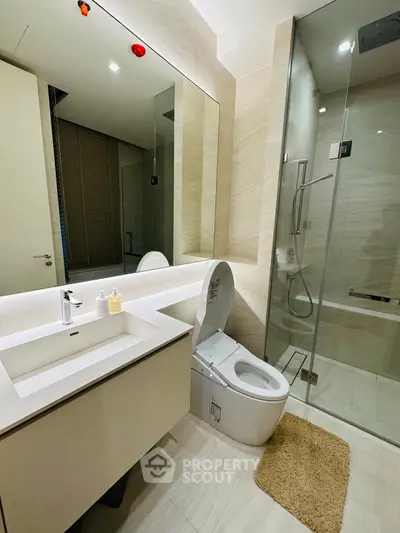 Modern bathroom with sleek design, featuring a glass shower and elegant fixtures.