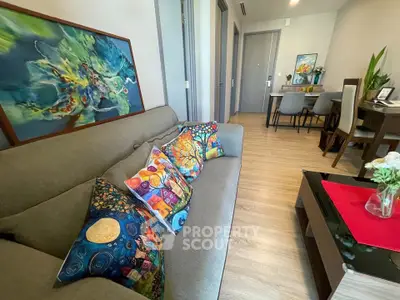 Stylish living room with vibrant decor and modern dining area in open layout apartment.