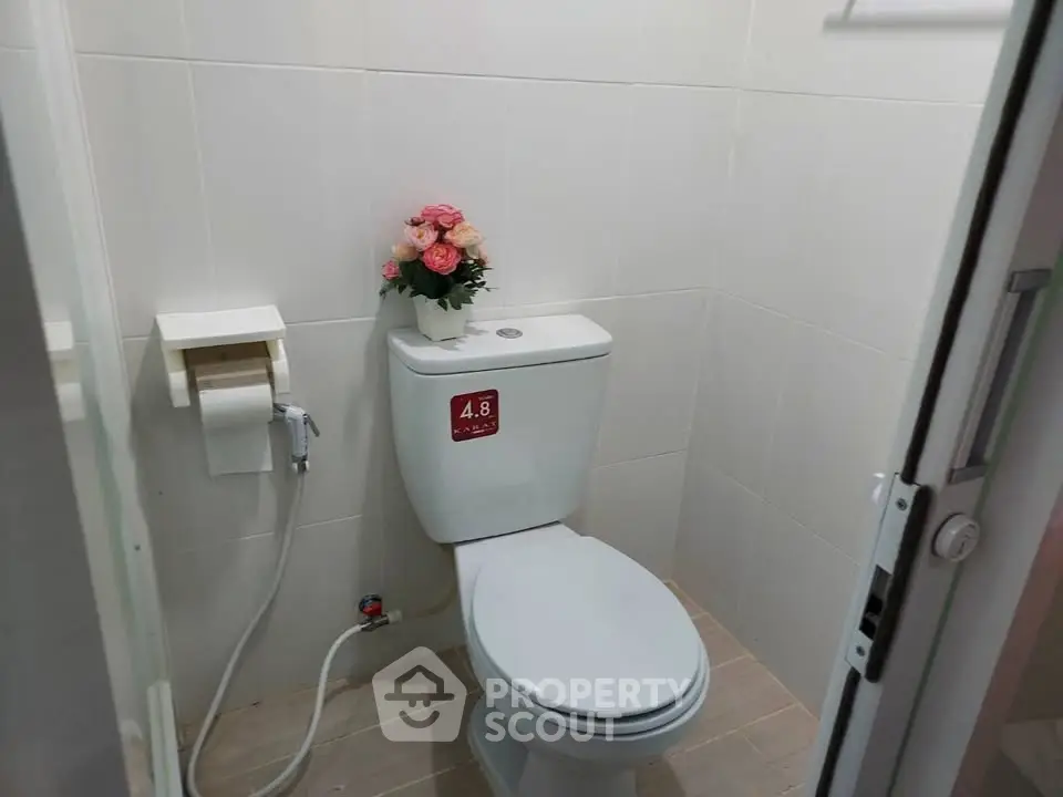 Compact bathroom with modern toilet and floral decor, ideal for small spaces.