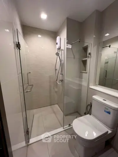 Modern bathroom with glass shower enclosure and sleek fixtures in a contemporary apartment.