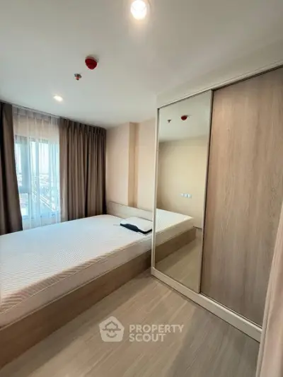 Modern bedroom with large window and mirrored wardrobe in a stylish apartment.