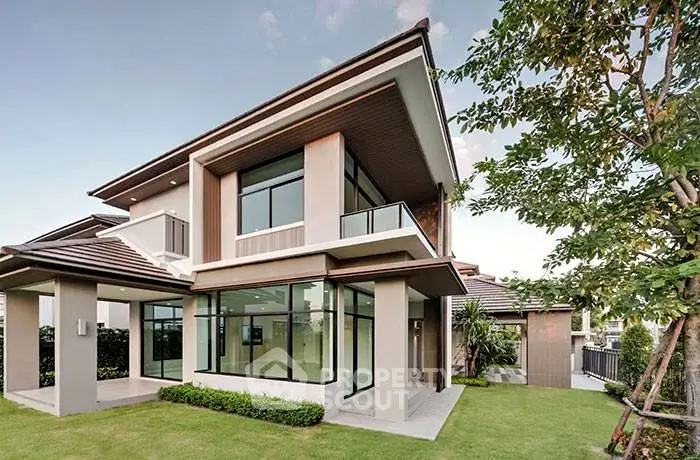 Modern two-story house with large windows and lush green lawn, perfect for family living.