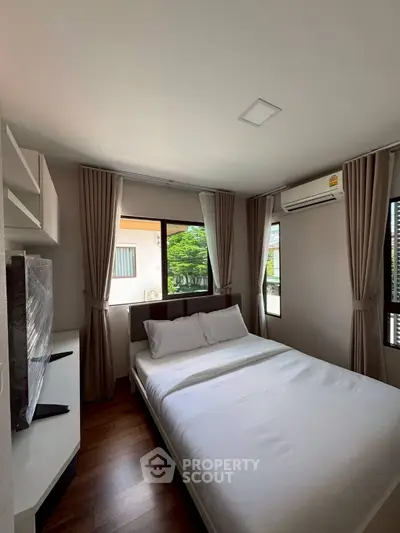 Cozy bedroom with large windows and air conditioning, perfect for relaxation and comfort.