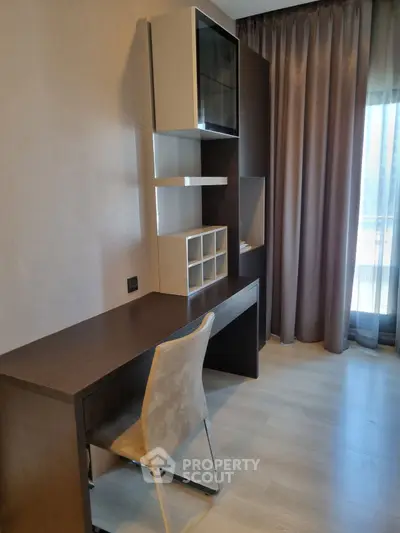 Modern study area with sleek desk and chair, featuring built-in shelving and natural light.
