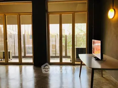 Modern living room with large windows and sleek TV setup, perfect for urban living.