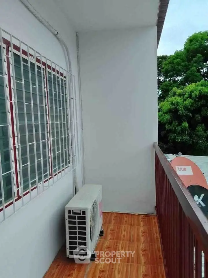 Charming balcony with wooden flooring and lush green view, perfect for relaxation.