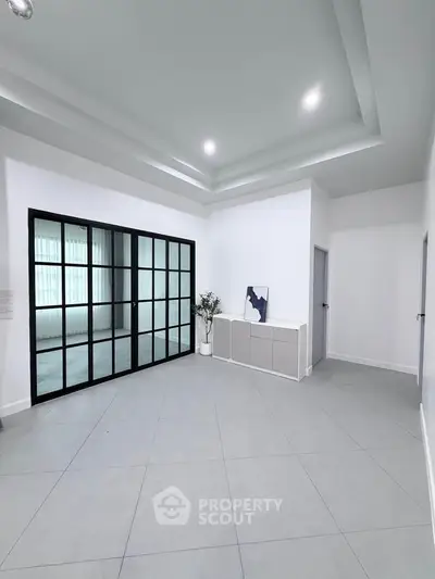 Spacious modern living room with sleek tile flooring and elegant glass doors.