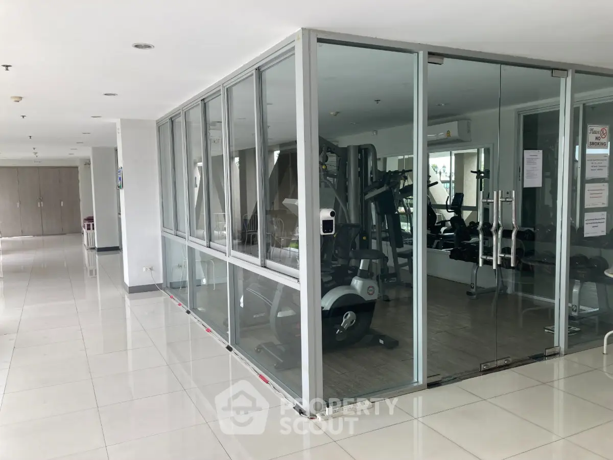 Modern gym with glass walls in a residential building, featuring state-of-the-art fitness equipment.