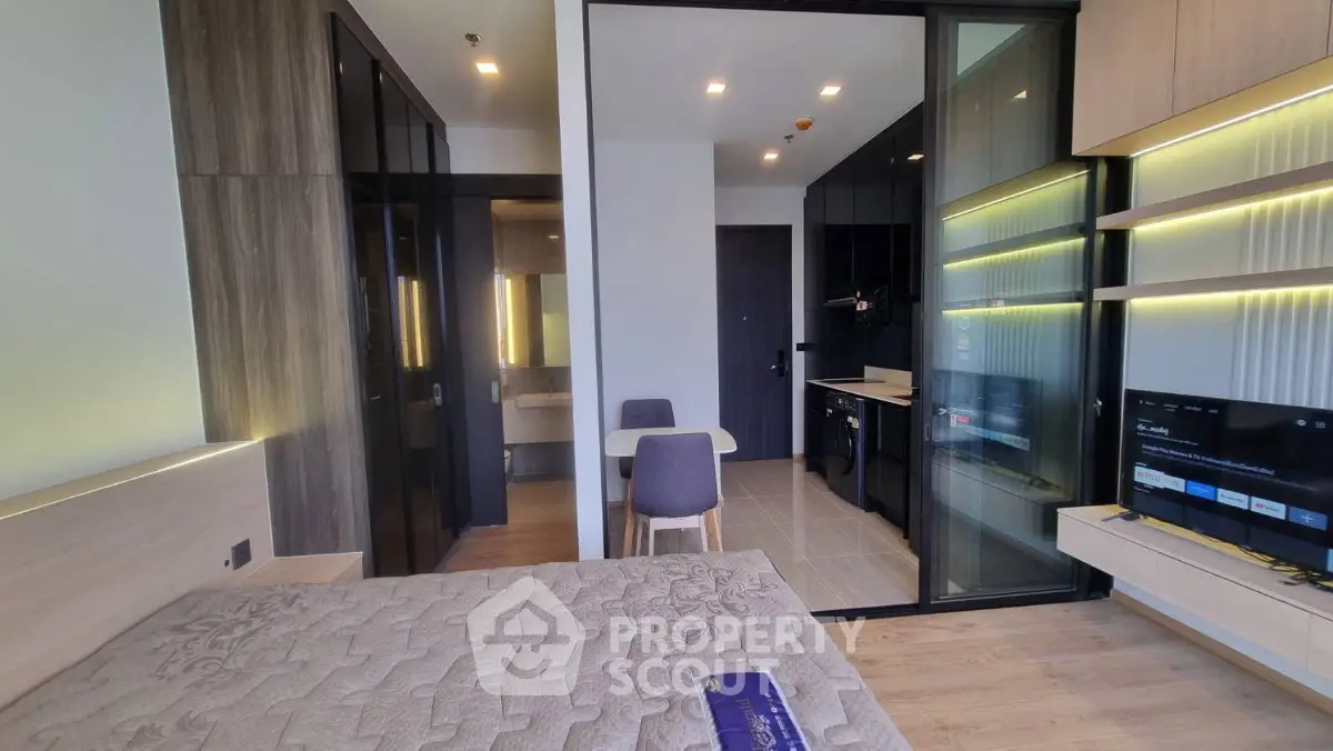 Modern studio apartment with sleek kitchen and cozy living area, featuring stylish lighting and contemporary design.