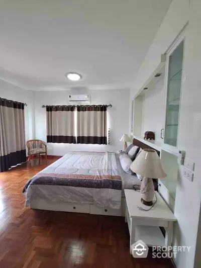 Spacious bedroom with elegant decor and natural light, featuring a comfortable bed and stylish furnishings.