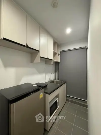 Modern compact kitchen with sleek cabinets and appliances in a cozy apartment.