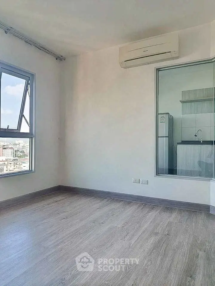 Modern unfurnished apartment with air conditioning and city view, featuring sleek flooring and a compact kitchen.