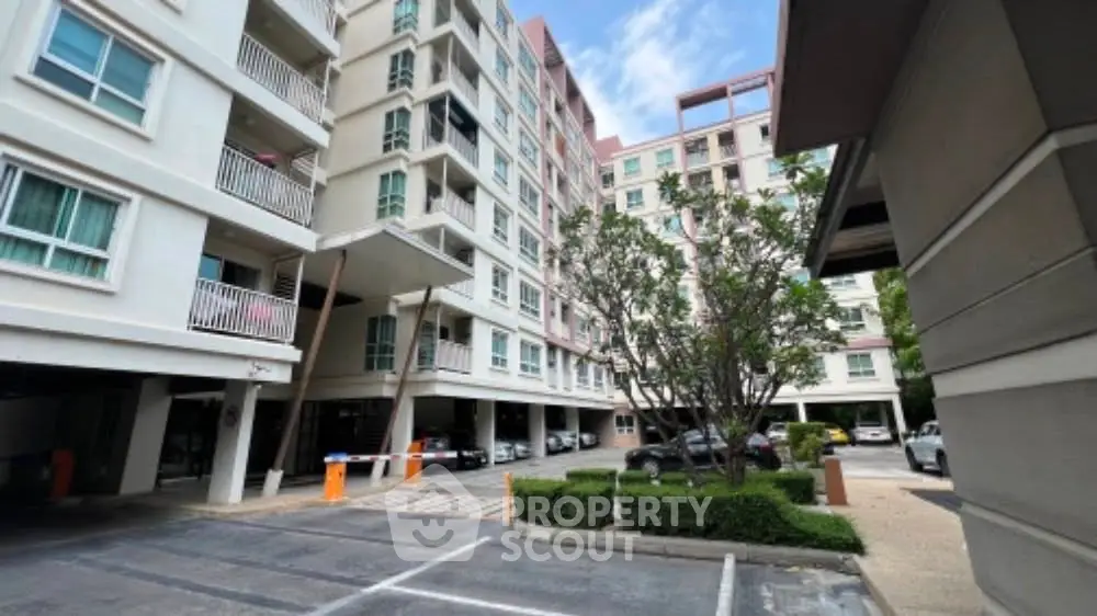 Modern apartment building with parking area and landscaped greenery.