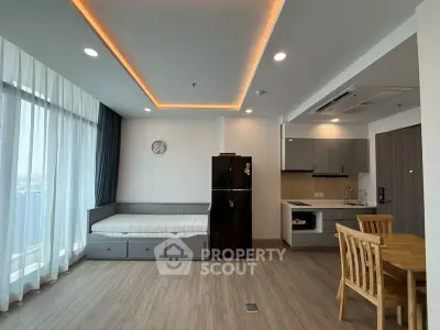 Modern open-layout living room with kitchen, featuring sleek design and natural light.