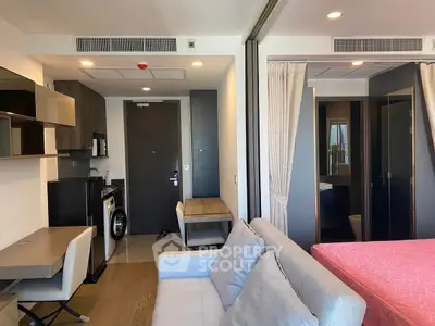 Modern studio apartment with compact kitchen and cozy living area, featuring a washing machine and stylish decor.