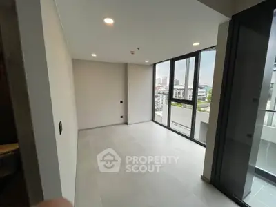 Spacious modern room with large windows and city view, perfect for urban living.