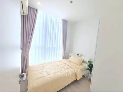Bright and cozy bedroom with large window and modern decor, perfect for relaxation.