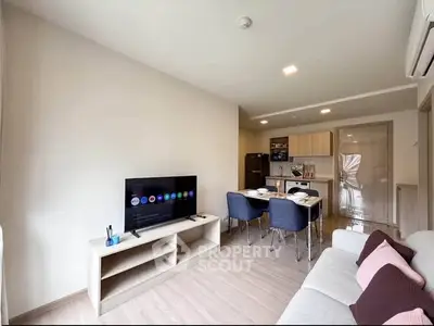 Modern living room with open kitchen, stylish furniture, and natural light.