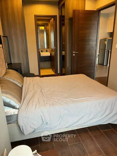 Modern bedroom with wooden flooring and ensuite bathroom in a stylish apartment.