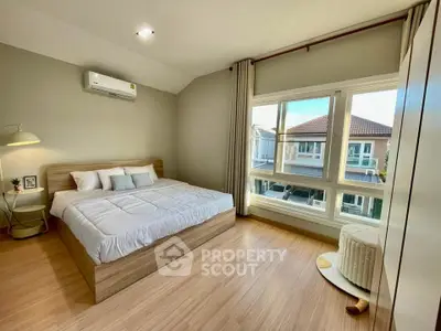 Spacious bedroom with large window and modern decor in a stylish home.