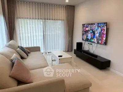Modern living room with large sofa and flat-screen TV, perfect for relaxation and entertainment.