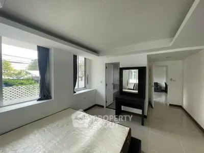 Spacious bedroom with large windows and modern furnishings in a bright apartment.